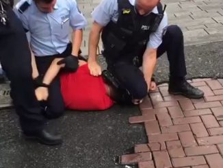 Polizist kniet auf Nacken eines