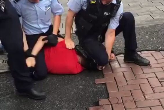 Polizist kniet auf Nacken eines